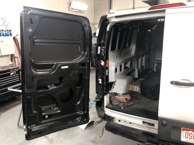 A white van with the door open in a garage.