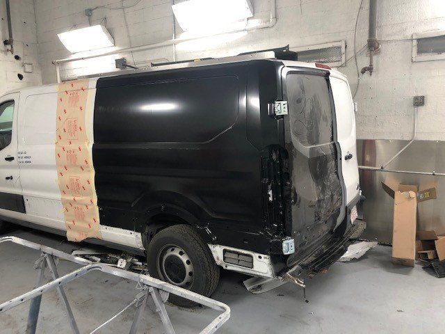 A black and white van is being painted in a garage.