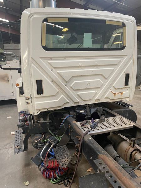 The back of a white truck is sitting in a garage.