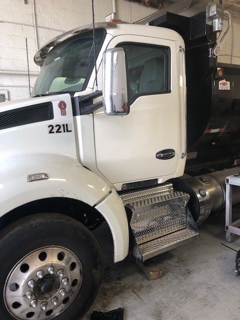 A white truck with the number 221l on the side is parked in a garage.