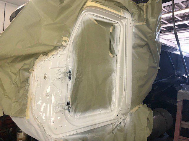 A car door is being painted in a garage