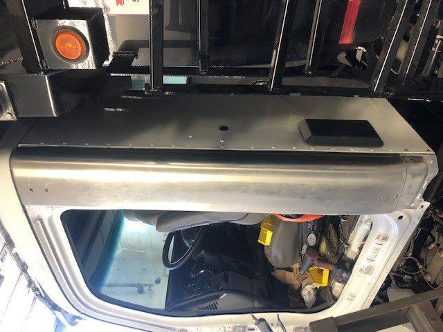 The inside of a truck with the door open and a ladder on top of it.