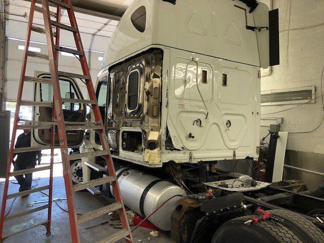 A white semi truck is being repaired in a garage.