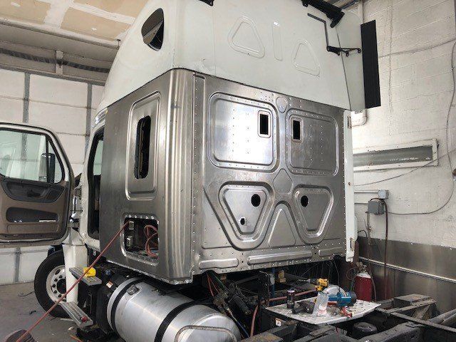 A semi truck is being repaired in a garage.