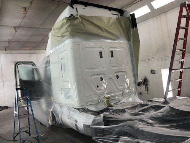 A white truck is being painted in a paint booth.