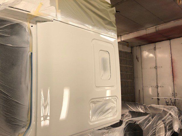 A white truck is being painted in a paint booth.