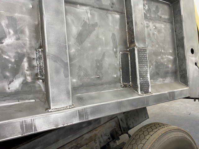 A dump truck is sitting on the ground in a garage.