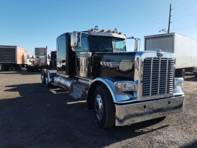 A black semi truck is parked in a parking lot.