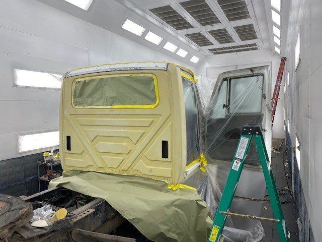 A truck is being painted in a paint booth.