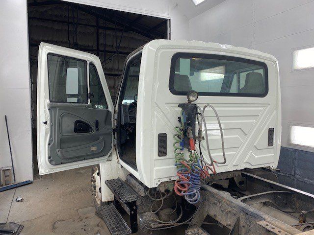 A white truck is sitting in a garage with its doors open.