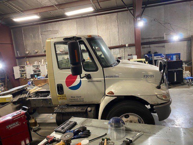 A white tow truck with a pepsi logo on the side is parked in a garage.
