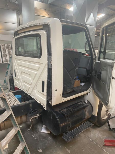 A white truck is sitting in a garage with the door open.