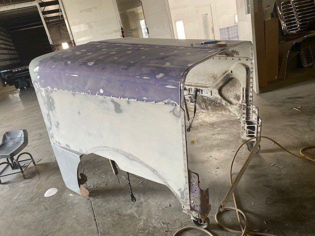 A hood is being painted in a garage.