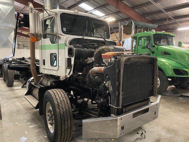 A white and green semi truck is sitting in a garage.