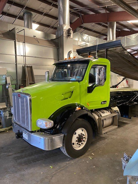 A green tow truck is parked in a garage.