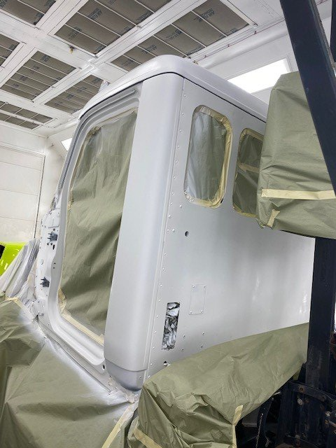 A white truck is being painted in a paint booth.
