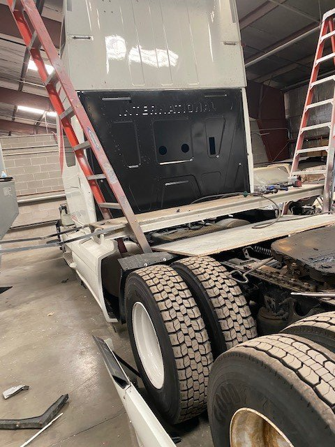 A semi truck is being worked on in a garage.