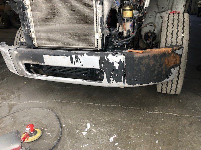 The front bumper of a truck is being repaired in a garage.