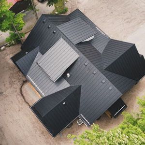An aerial view of a complex, multi-gabled roof covered in dark grey metal standing-seam roofing.