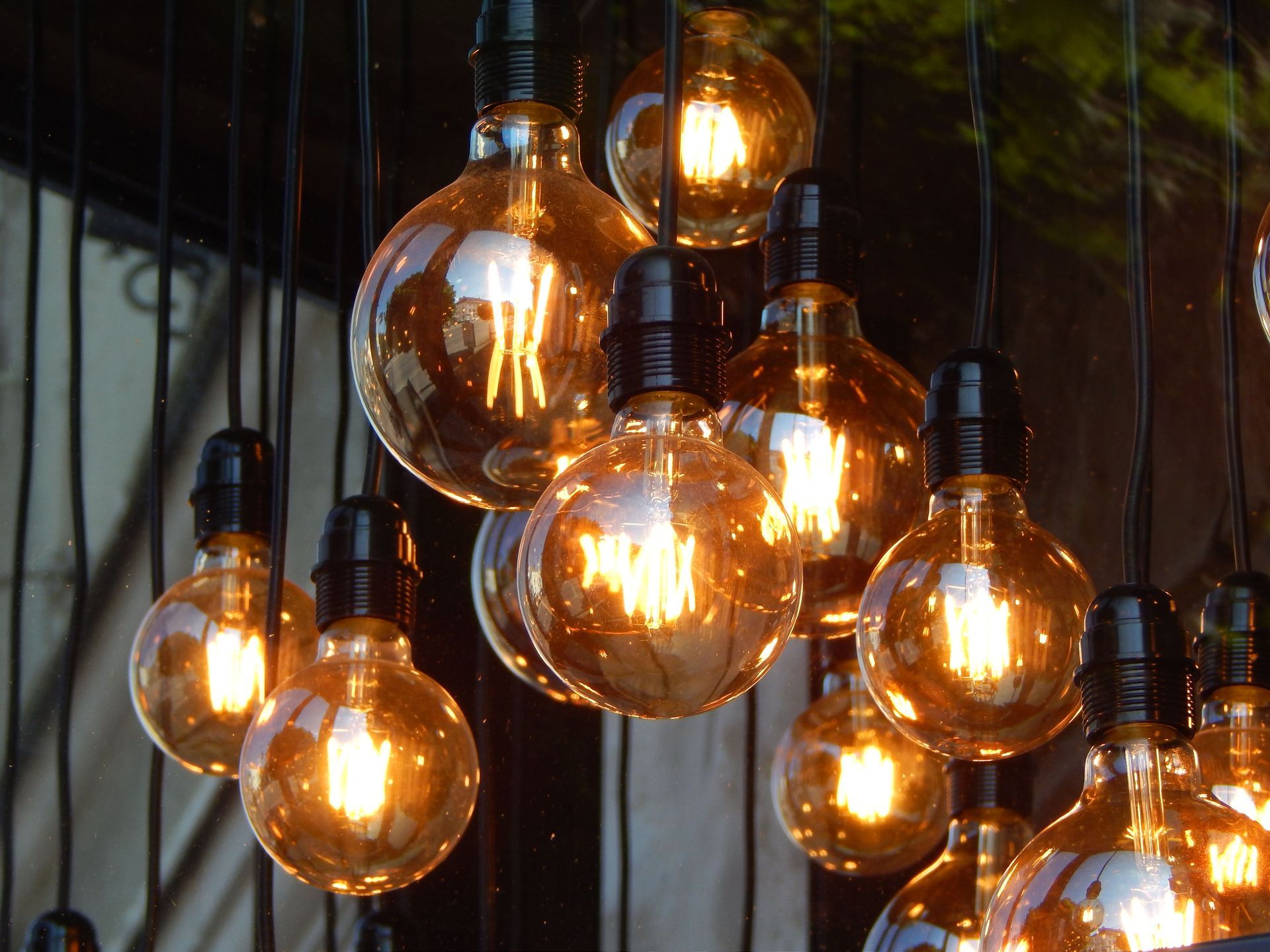 Cluster of glowing amber Edison bulbs hanging against a dark background