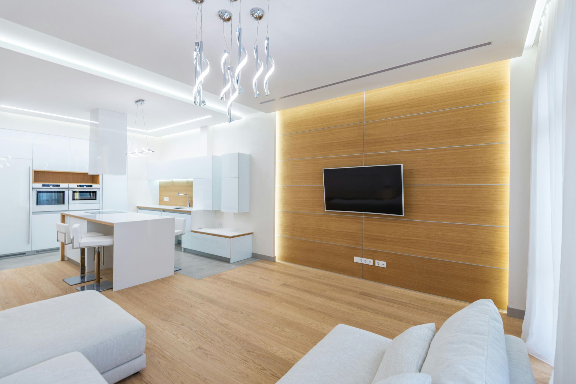 Bright modern open-plan living room and kitchen with wood accent wall and wall-mounted TV