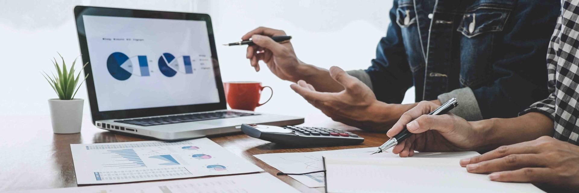 A group of people are sitting at a table looking at a laptop computer.
