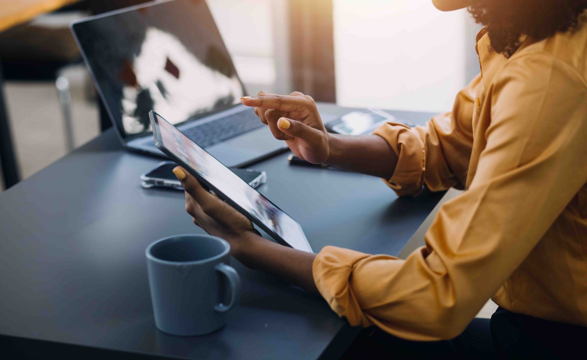 A woman is sitting at a table using a tablet computer.