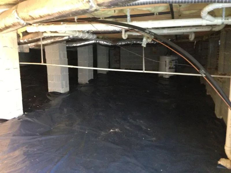 An empty basement with a black tarp on the floor