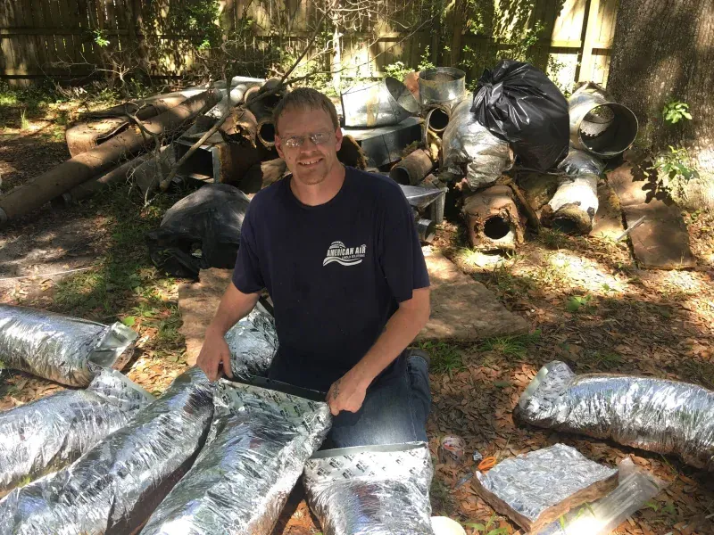 A man is kneeling down in front of a pile of trash.