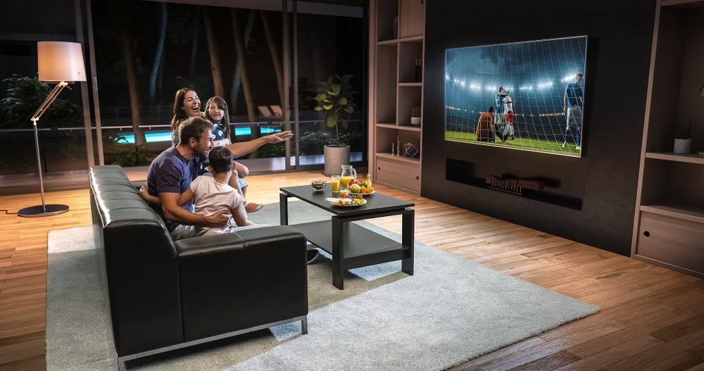 A Family Is Sitting On A Couch Watching A Football Game On A Television —  Craig's TV/Antenna Services In Lake Macquarie, NSW