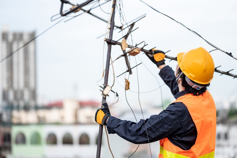 An Electrician Is Working On A Power Line On Top Of A Building —  Craig's TV/Antenna Services In Maryland, NSW