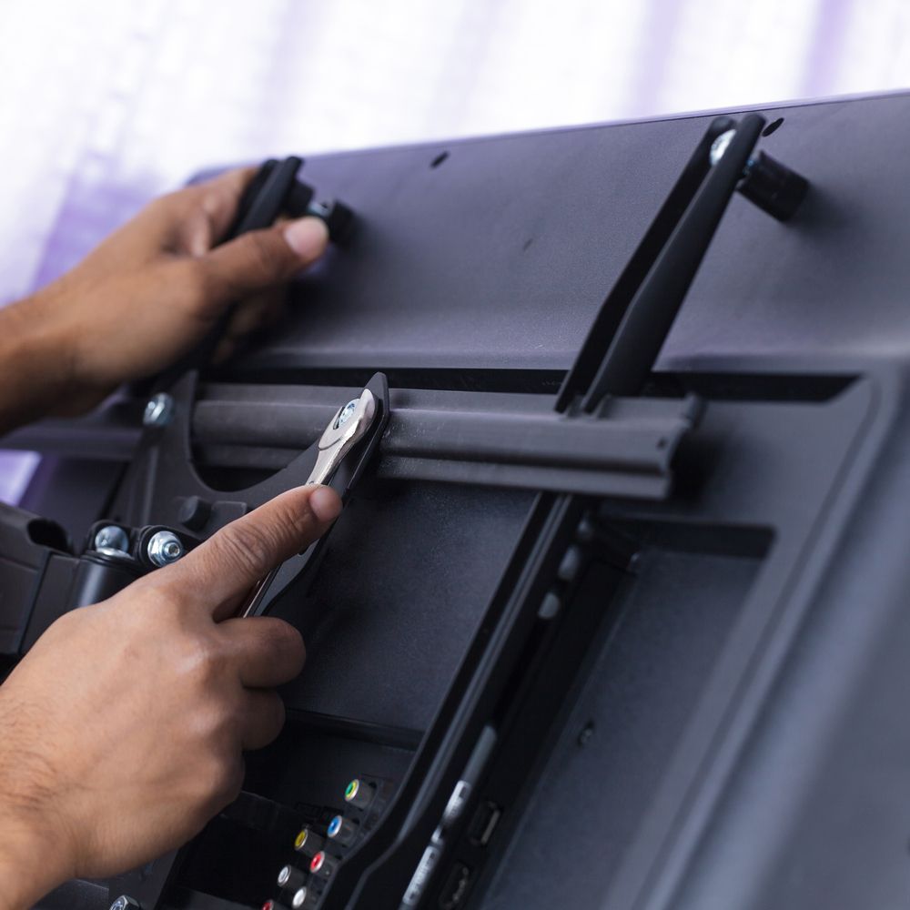 A Person Is Holding A Pair Of Pliers Over A Television — Craig's TV/Antenna Services In Maitland, NSW