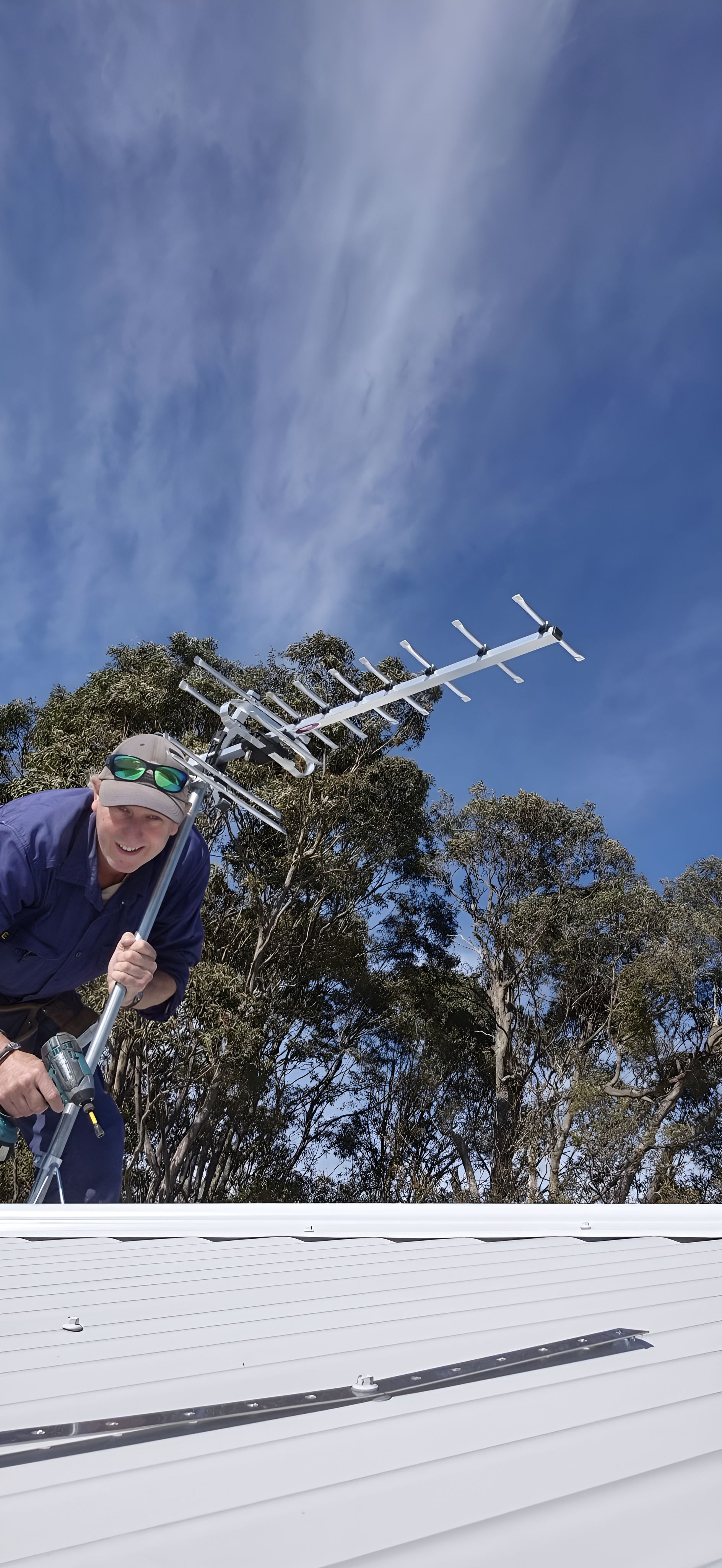 A Man Is Working On A Roof With An Antenna In The Background — Craig's TV/Antenna Services In Maryland, NSW