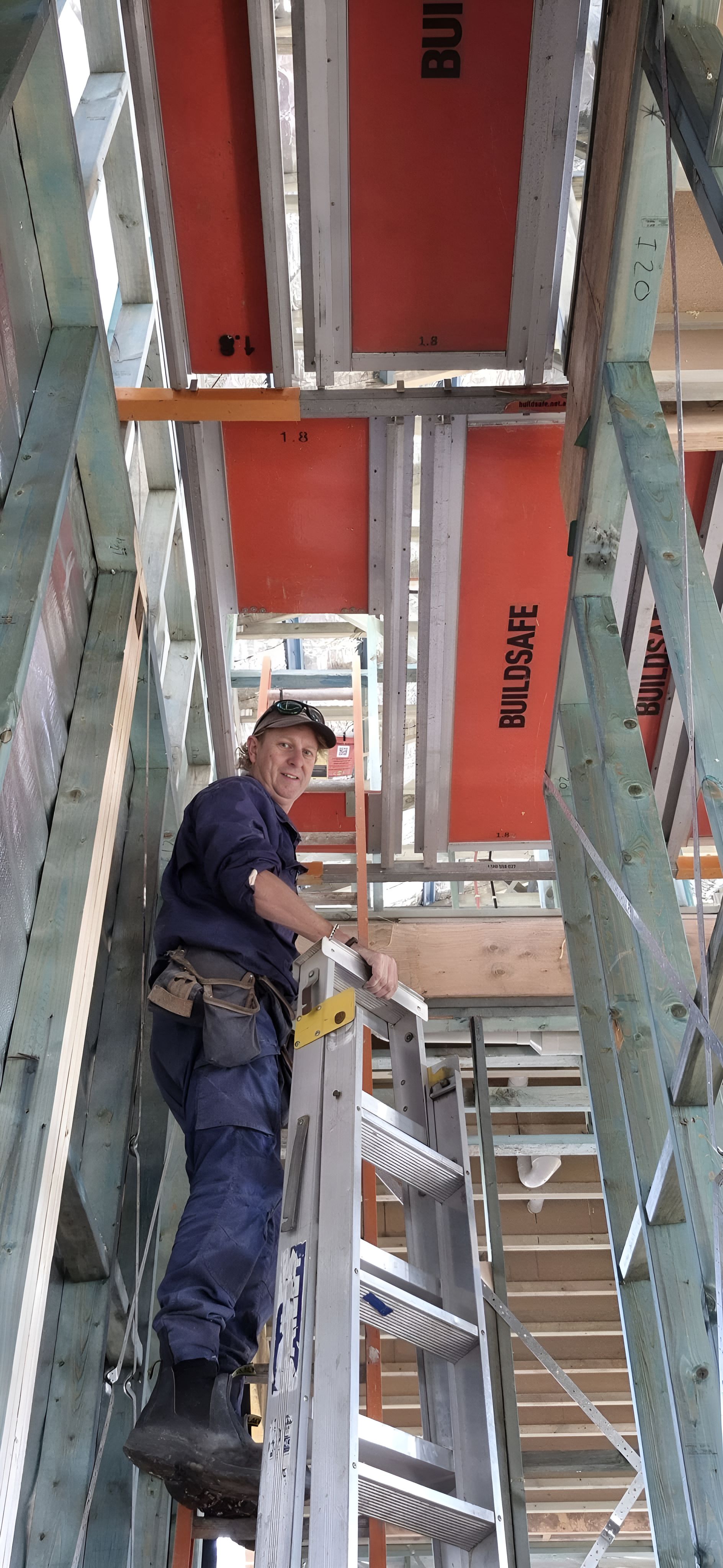 A Man Is Standing On A Ladder In A Building — Craig's TV/Antenna Services In Maryland, NSW