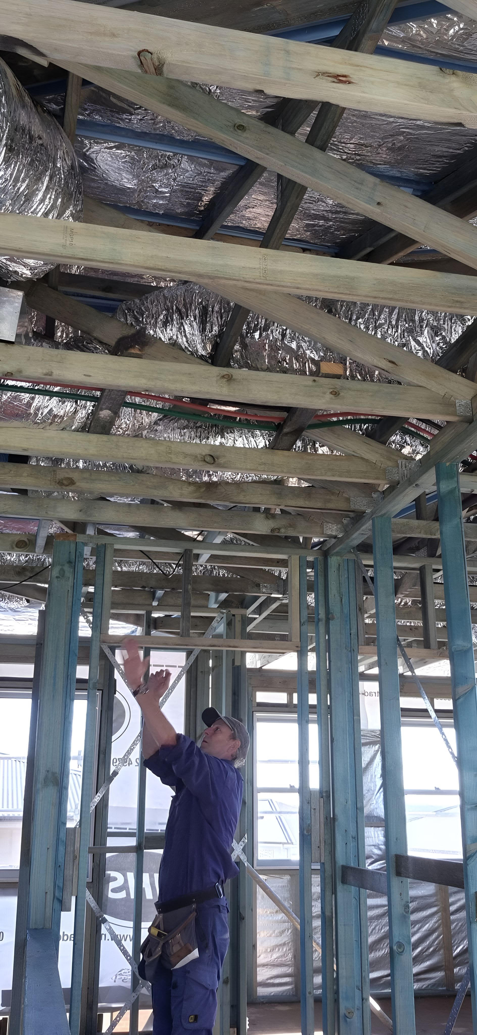 A Man Is Working On The Ceiling Of A Building — Craig's TV/Antenna Services In Lake Macquarie, NSW