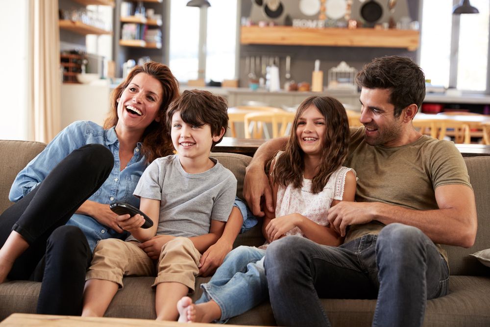 A Family Is Sitting On A Couch Watching Tv Together — Craig's TV/Antenna Services In Maryland, NSW