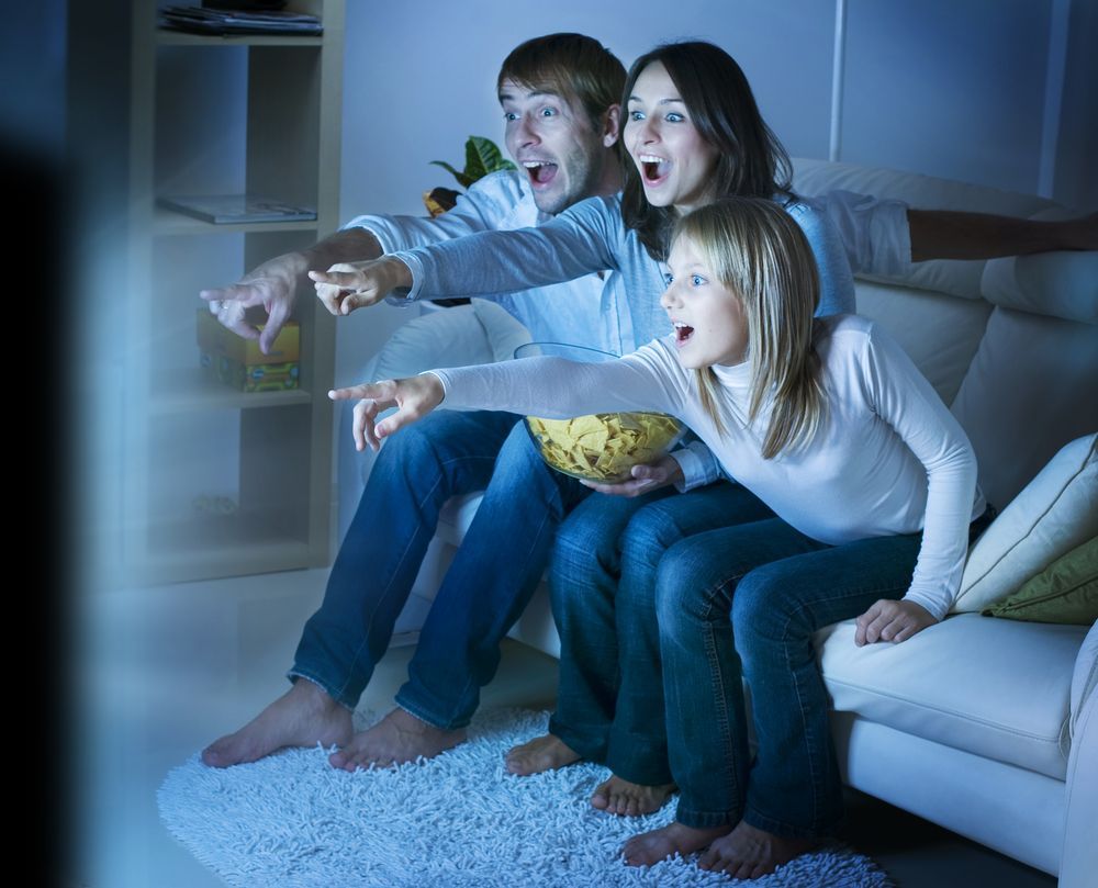 A Family Is Sitting On A Couch Watching Tv —  Craig's TV/Antenna Services In Cameron Park, NSW