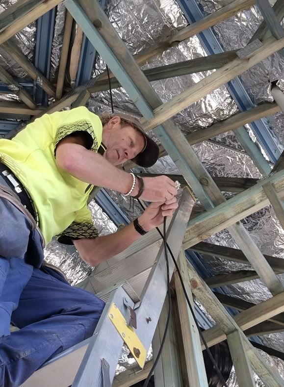 A Man Is Standing On A Ladder Working On A Roof — Craig's TV/Antenna Services In Maryland, NSW