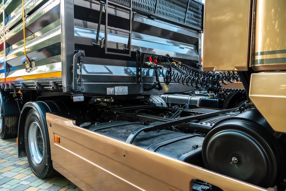 Empty flatbed truck chassis at a loading dock, showing black frame and tan side panels. — Aust. Advanced Trailer Sales & Service in Berrimah, NT