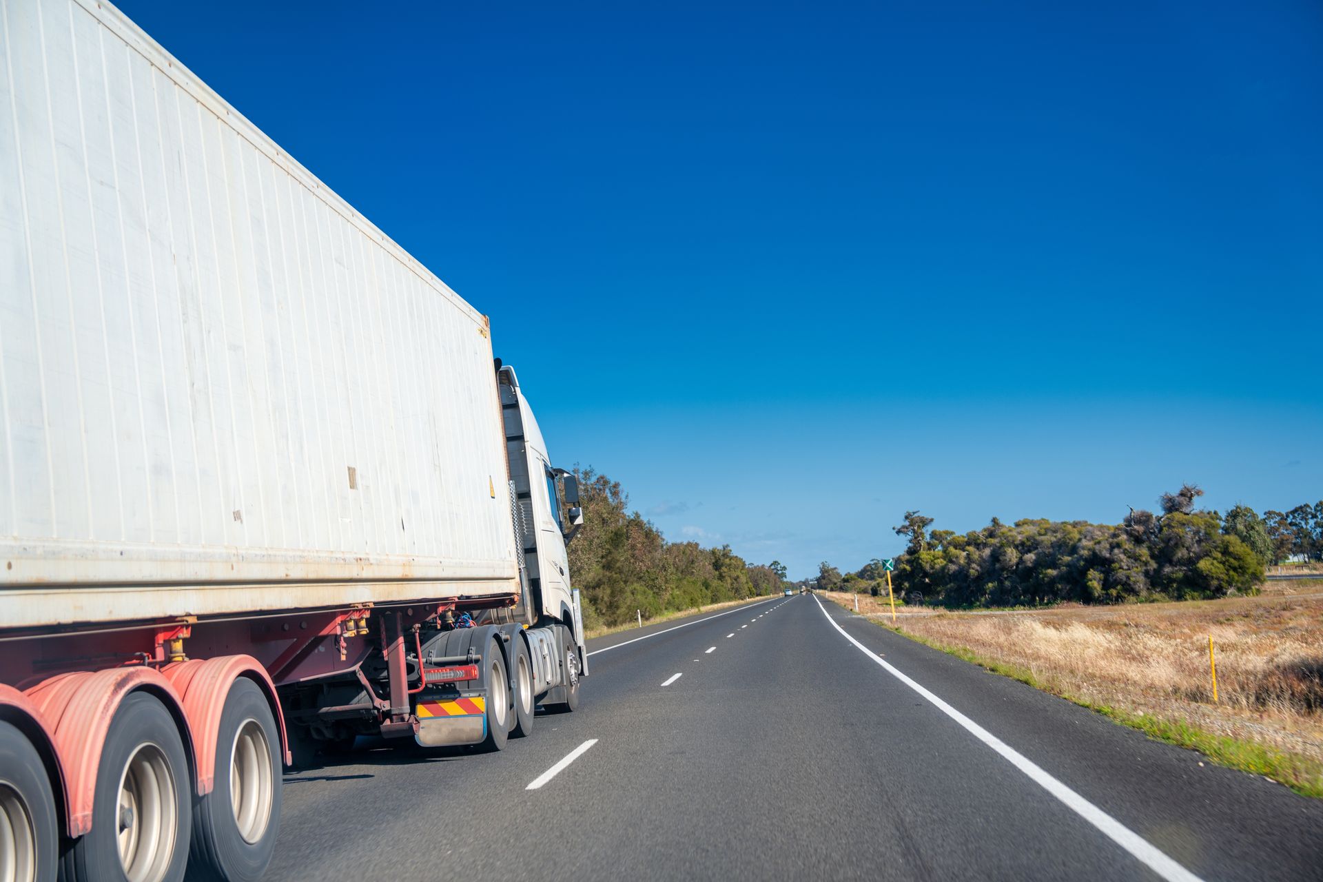 A White Semi-Truck Driving on A Sunny Highway — Aust. Advanced Trailer Sales & Service in Berrimah, NT