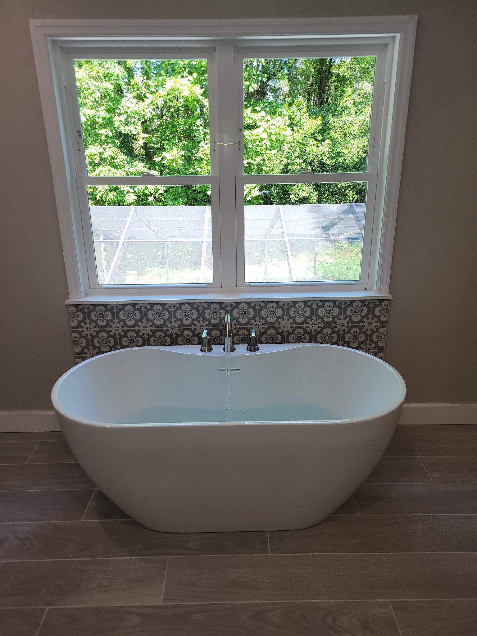 Two plumbers in a bathroom renovating, working on pipes and walls.