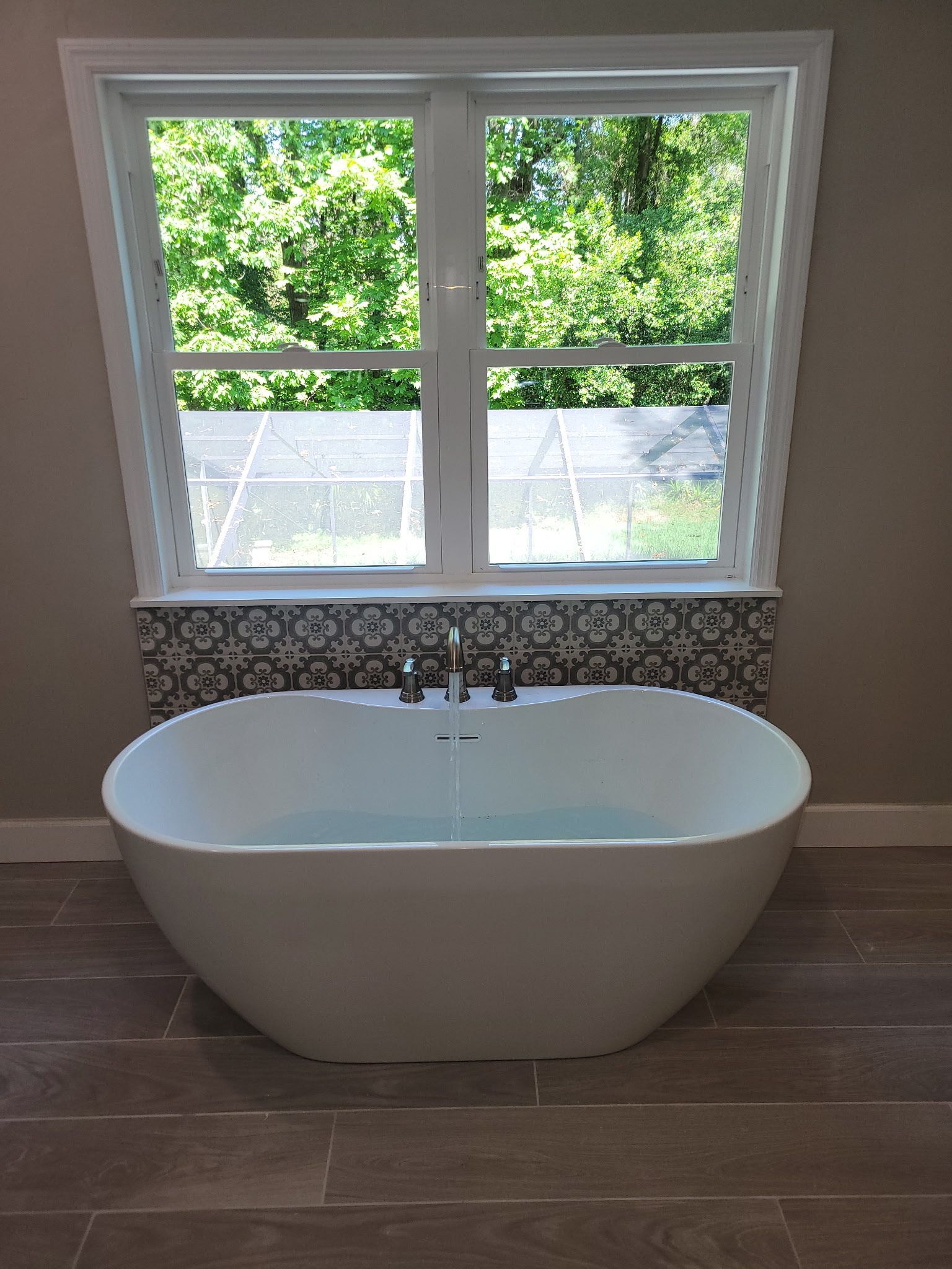 Lush green lawn with striped mowing pattern, trees, and blue sky with clouds.