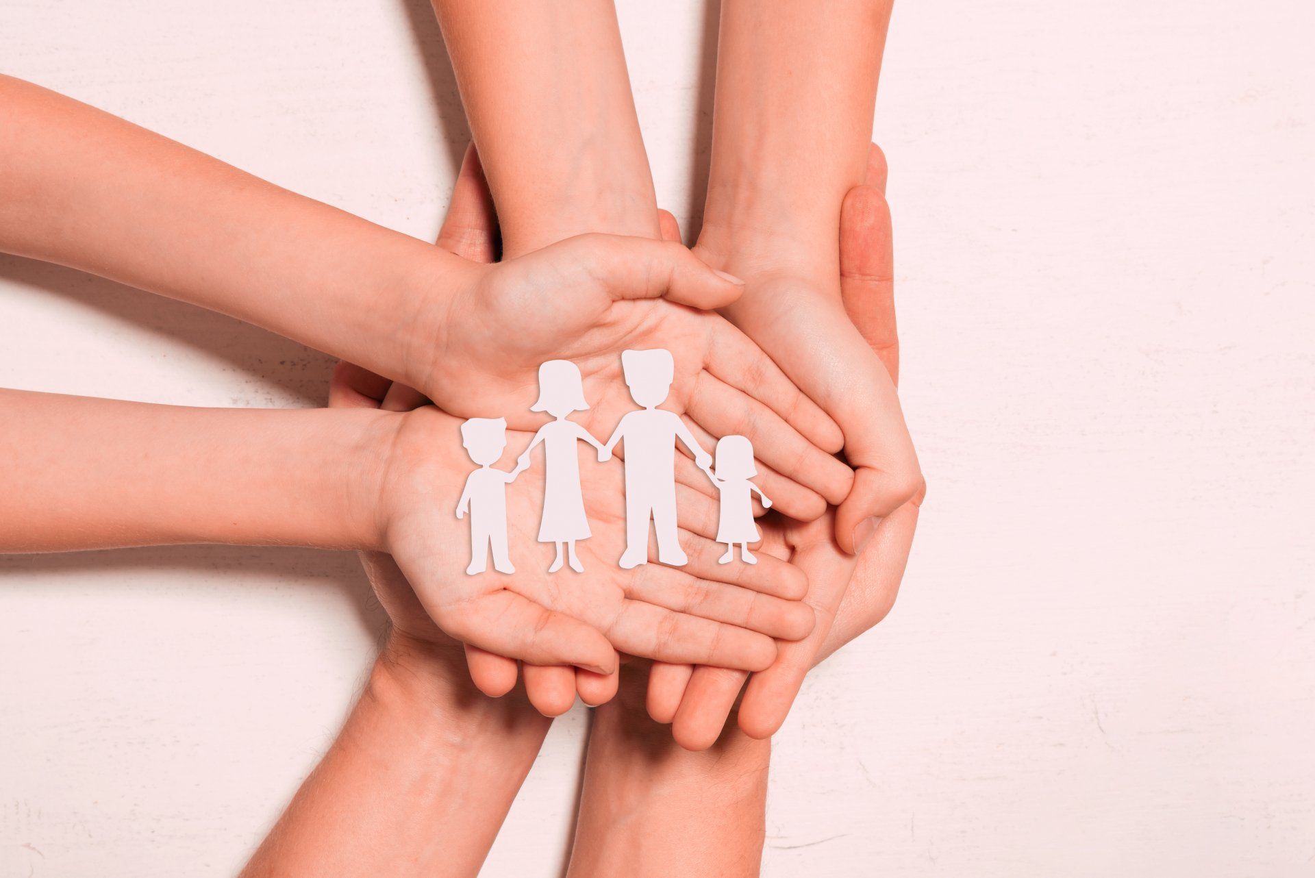 Hands holding a paper cutout family, representing unity and support.