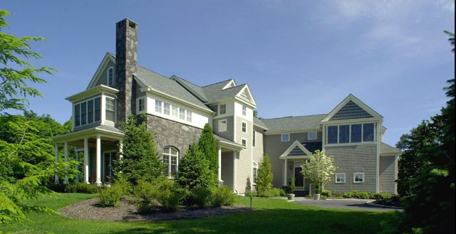 Large house with multiple sections, green lawn, trees, blue sky.