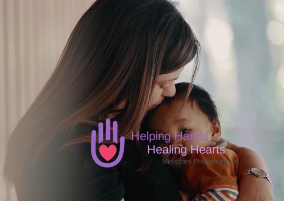 Woman kissing a baby's head. Helping Hands Healing Hearts logo is in the foreground.