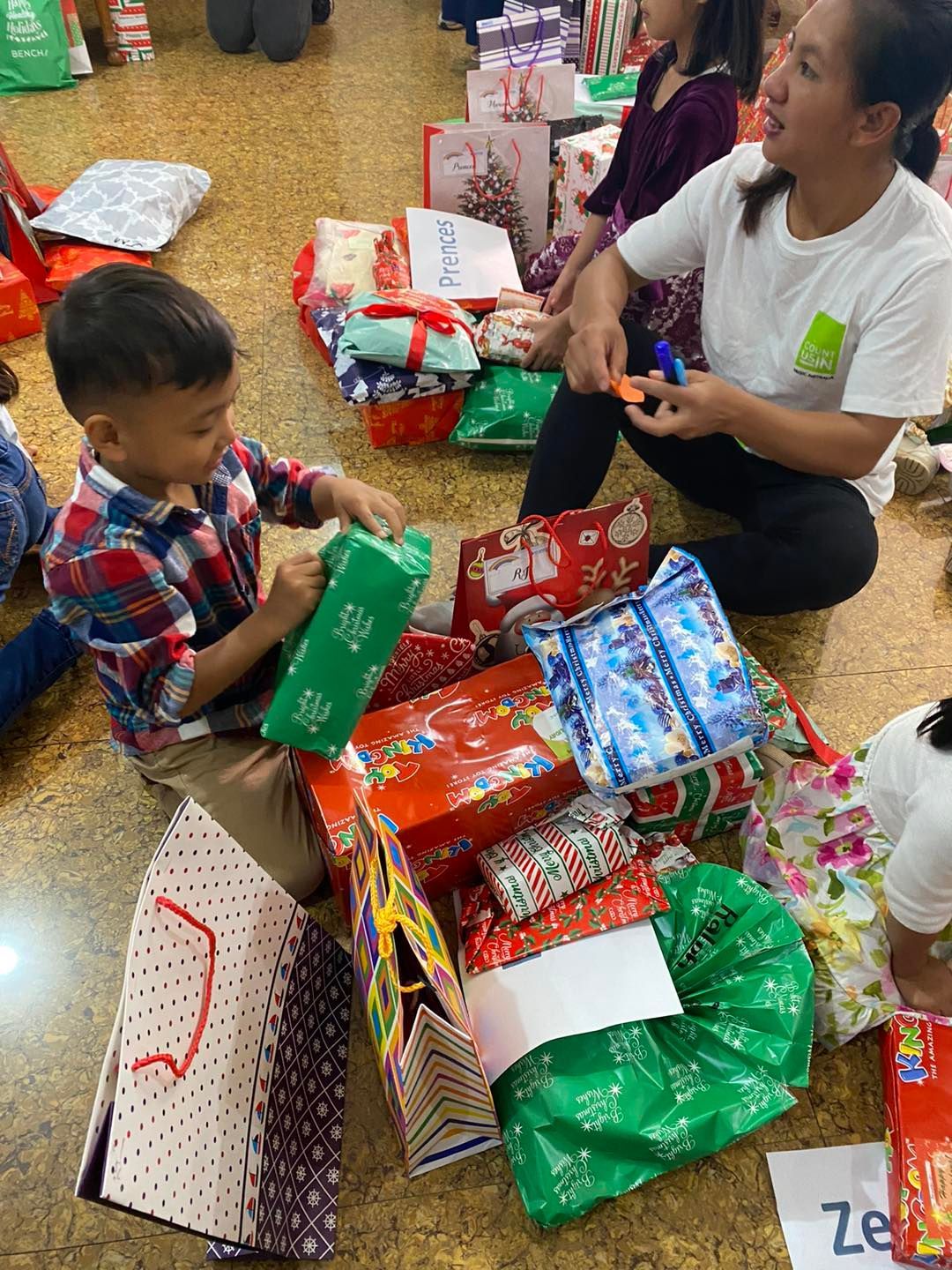Person playing an acoustic guitar, fingers on frets. Red and green stage lighting.