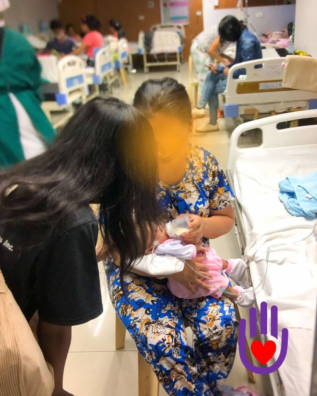 People in a crowded room with hands raised, singing with expressive faces.