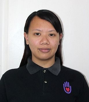 Woman in black polo shirt with hand logo, looking at the camera.