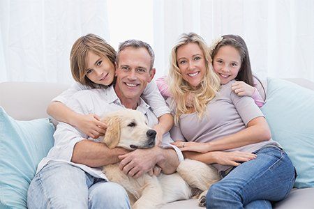 Apartment Rental — Cute Family Relaxing Together On The Couch With Their Dog in Morton, IL