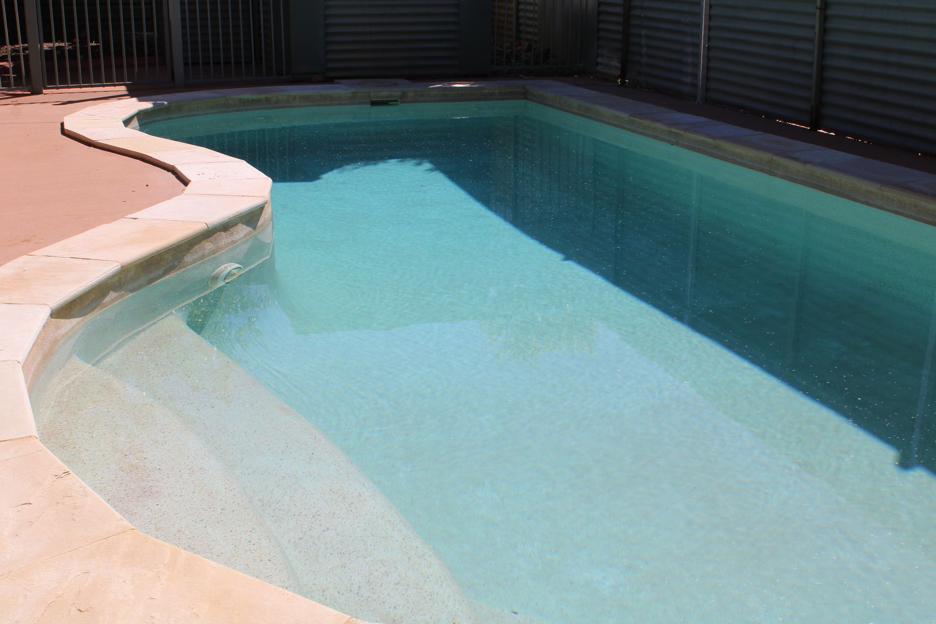A large swimming pool with a fence in the background.